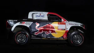 Toyota Hilux DKR GR FC vätgasdriven racerbil med Red Bull-logotyp, sponsorlogotyper och Qatar 2022-märkning på svart bakgrund.